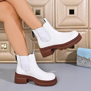 Women's white Chelsea boots with brown chunky lug platform sole, detail shot showing side gore.