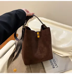 Detailed view of the dark brown suede bucket bag, featuring golden turn-lock and handle.