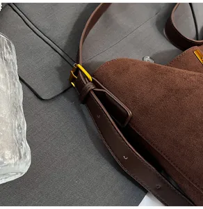 Close-up of brown suede retro shoulder bag strap, metal buckle detail, premium texture.