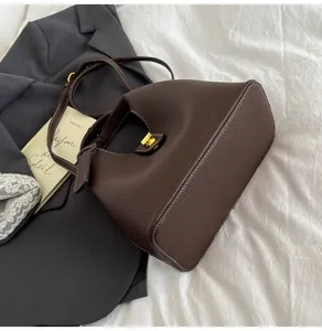 Dark brown leather bucket bag detail shot, featuring metal lock closure and strap.