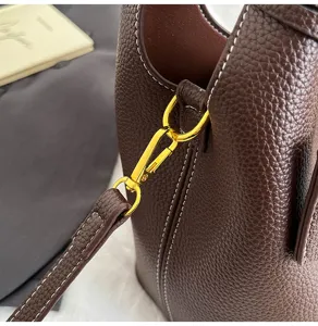 Detailed view of brown leather bucket bag with gold hardware and white stitching texture close-up