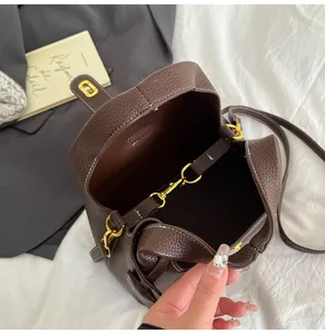 Detailed view of brown pebbled leather bucket bag featuring gold tone hardware and fine stitching.