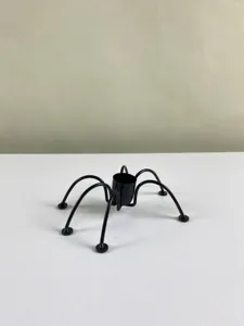 Iron spider candle holder detail shot, black metal gothic home decor and Halloween prop.