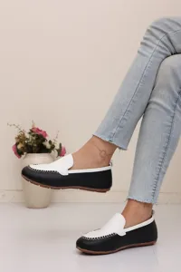 Schwarze weiße Slipper flache Freizeitschuhe Detailansicht mit weicher Sohle und Naht.