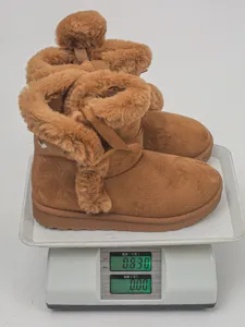 Brown winter snow boots for women with plush lining, cute bow, and fluffy ball decoration.