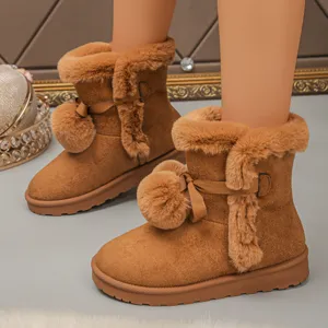 Brown winter snow boots detail closeup featuring plush faux fur trim, cute pom-pom bow and thick sole.
