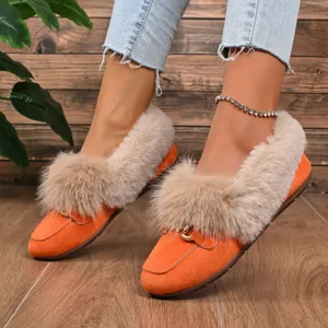 Détail de mocassins plats pour femmes en daim orange fourrés avec mors de cheval métallique.
