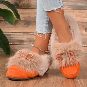 Close-up detail of cozy winter fleece-lined flat cotton shoes with fluffy fur and bow.