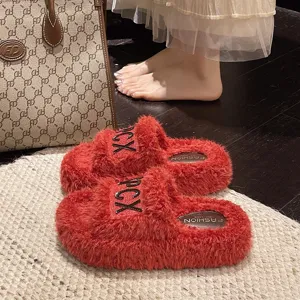 Vista dettagliata di pantofole soffici rosse con zeppa in lana d'agnello e cinturino con lettere.