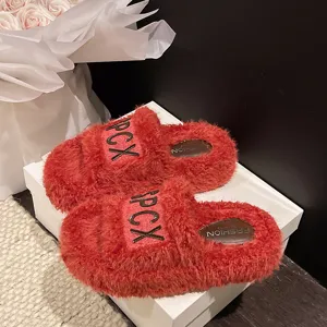 Primo piano di pantofole platform soffici rosse da donna con dettagli di lettere e morbido peluche.