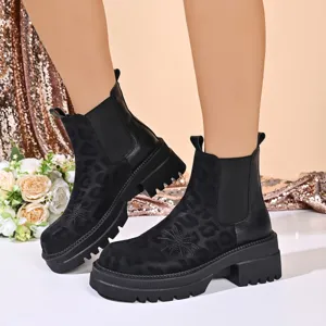 Close-up detail of black platform Chelsea boots with subtle leopard print and floral embroidery.