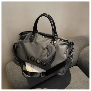 Detail view of large capacity grey travel duffel gym bag with letters and shoulder strap.