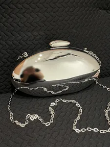 Silver metallic oval evening clutch bag with chain strap for women elegant party shoulder bag.