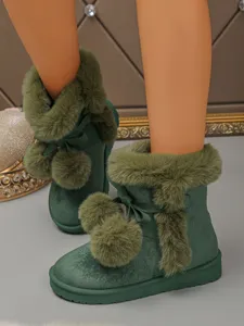 Green snow boots detail showing plush lining, cute bow and fluffy pom-pom decorations.