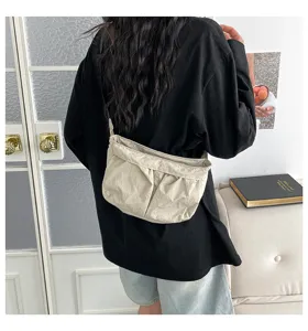 Detailopname van de casual beige crossbody stoffen tas gedragen in een licht interieur.