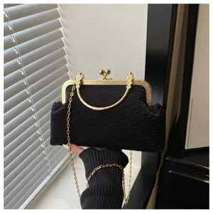 Elegant black evening clutch bag with gold chain strap and vintage clasp closure detail.