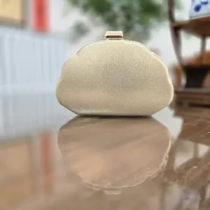 Gedetailleerde close-up van de elegante gouden avondtas met metallische glans en nette sluiting.