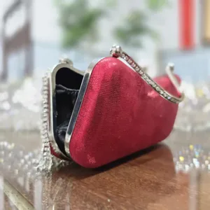 Red velvet evening clutch detail showing crystal rhinestones, metallic frame and side tassels.