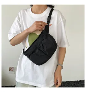 Gedetailleerd overzicht van de zwarte nylon schoudertas gedragen door model, toont textuur.