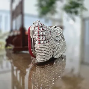 Detailed view of luxury red rhinestone evening clutch bag with crystal fringe and metal frame.