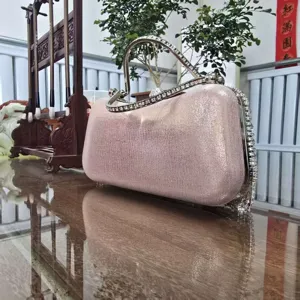 Pink glitter evening clutch bag with rhinestone handle detail, elegant party handbag.