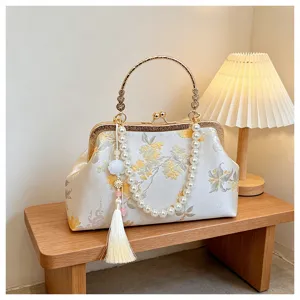 Dettaglio della splendida borsa a mano a conchiglia ricamata con manico di perle.