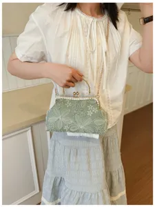 Green embroidered kiss-lock evening bag with metal handle and chain for women fashion style.