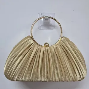 Gold pleated evening bag detail, featuring an elegant metallic round handle for party wear.