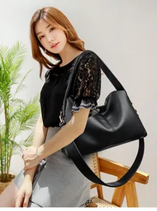 Detail shot of stylish black leather shoulder bag worn by model, showing texture and strap.
