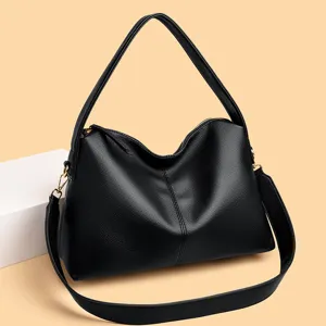Detailed view of the black leather shoulder bag showing texture, metal hardware and strap.