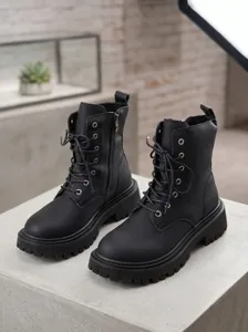 Detailansicht schwarzer Plateau-Kampfstiefel mit dickem Absatz, Schnürung und Reißverschluss.