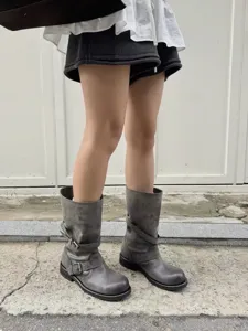 Detail shot of vintage distressed leather buckle boots, showing textured grey finish.