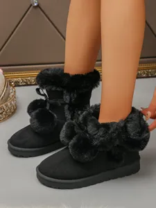 Detailed view of women black winter snow boots with cute plush pom poms, thick warm fleece lining.