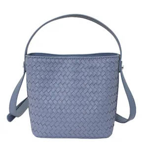 Detailed close-up view of stylish blue woven leather bucket bag with handle straps.