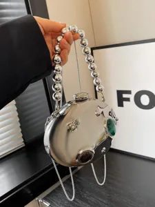 Borsa da sera metallica argentata con manico di perle e dettagli in pietra verde.