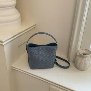 Minimalist soft leather woven bucket bag with top handle and crossbody strap for women.