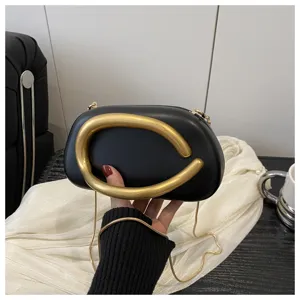 Chic sac bandoulière noir pour femme avec poignée sculpturale dorée et chaîne élégante.