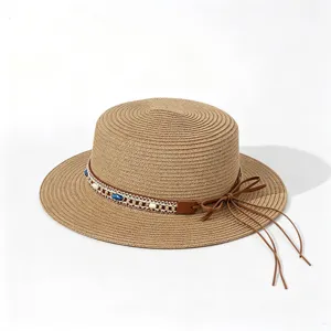 Detailed view of a straw sun hat featuring beaded bands and brown leather ribbon bow.