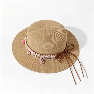 Ethnic style flat top straw sun hat, detailed view of woven ribbon and tassels for outdoor.