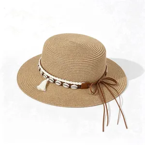 Bohemian straw boater sun hat featuring shell tassel band and leather bow detail for summer travel.