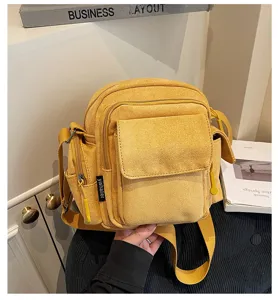 Close-up view of the yellow canvas crossbody camera bag featuring multi-pocket design.
