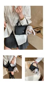 Detailed view of the black textured shoulder bag with a cute plush bunny charm and twist handle.
