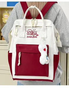 Detailaufnahme des kontrastfarbenen Rucksacks mit Fronttasche und süßem Plüschanhänger.
