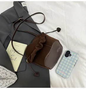 Dark brown suede bucket bag detail view with heart drawstring, flat lay photography.