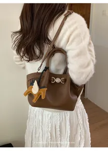Brown leather bucket shoulder bag with chic metal lock closure and cute horse charm accessory.