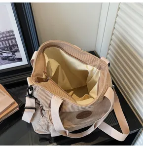 Detail view of the beige corduroy tote bag showing spacious interior lining and front pocket.