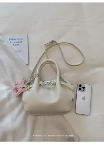 Minimalist white leather tote bag detail showing delicate hardware and matching pegasus charm.