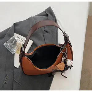 Detailansicht der trendigen braunen Hobo-Schultertasche mit stilvollem Baseballanhänger.
