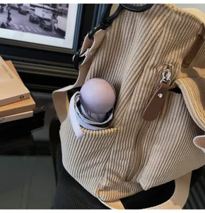 Corduroy shoulder bag detail shot, beige tote handbag pocket close up with mini umbrella inside.