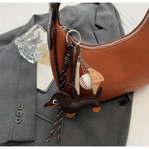 Schicke braune strukturierte Halbmond-Schultertasche Detail mit verspielten Anhaengern.